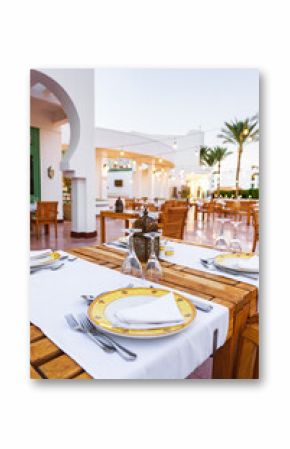 Relaxing outdoor dining setup at a coastal restaurant with elegant table settings in the evening