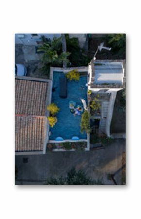 Aerial view of a cozy rooftop terrace where a woman relaxes with a white dog and lemonade. Surrounded by plants and blue tiles, the space evokes calm urban living and pet companionship
