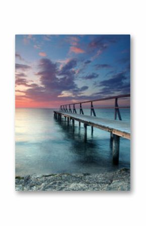 beautiful Vibrant Sunset Casting red Light on Weathered Wooden pier over the sea