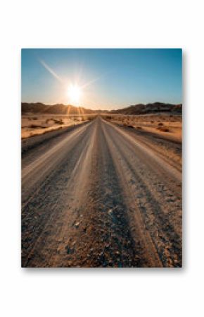 Desert Road at Sunset: A sun-kissed dirt road stretches into the horizon, framed by dunes under a clear blue sky.