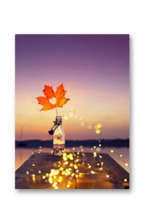 Seaside Romance: Glass Bottle and Autumn Leaf at Sunset
