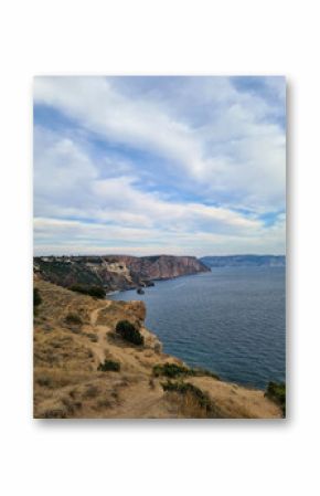 Coastal landscape with cliffs and ocean. The scene features a rocky shoreline, gentle waves, and a cloudy sky. Ideal for concepts of nature and tranquility.