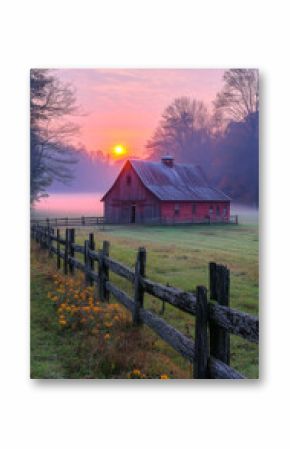 Beautiful sunrise over a rustic barn. A serene sunrise casts golden light over a charming red barn surrounded by a misty landscape and wooden fence.