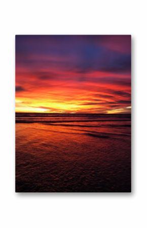 Vibrant tropical sunset over the ocean. The sky burns in shades of orange, red, and purple, reflecting on calm sea waves. Magical and dreamy moment of nature. Bali, Indonesia
