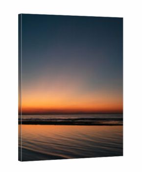 Tranquil seascape at sunset with vivid orange and blue gradient sky reflecting on calm ocean waves