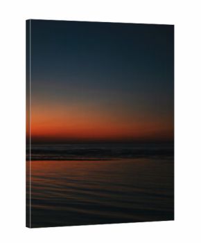 Tranquil seascape at sunset with vivid orange and blue gradient sky reflecting on calm ocean waves