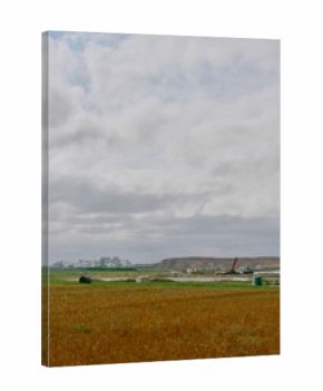 Wide view of a potash mining facility in Saskatchewan, Canada, featuring domed storage buildings, factory structures, red tailings pile, and cloudy prairie landscape in the foreground.