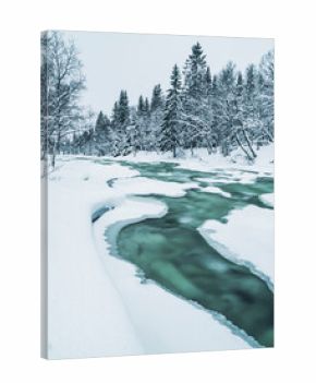 Frozen river flows through snowy landscape in Sweden during winter season