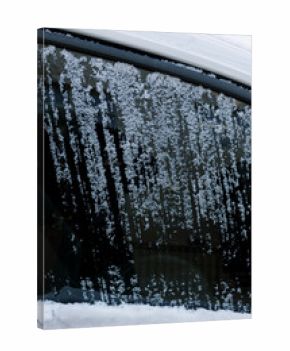 Frozen snow covers car window while streaks show where it has been scraped off on a cold winter morning