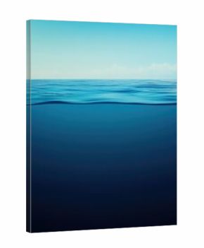 Calm blue sea split view, clear sky above, tranquil underwater gradient below showing serene ocean depth and glassy horizon reflection