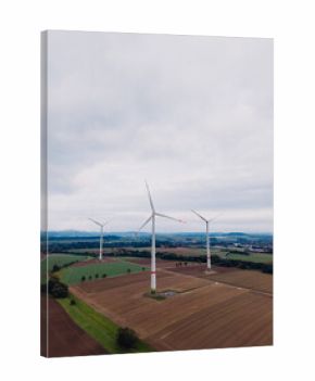 View of wind turbines spinning gently on a cloudy day in a vast green and brown landscape showcasing renewable energy use in agriculture