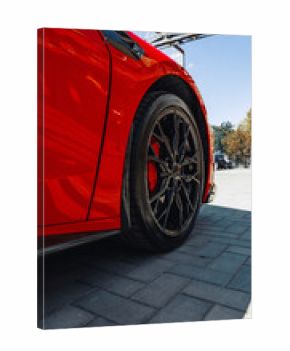 Bright red sports car parked on textured pavement under clear blue sky