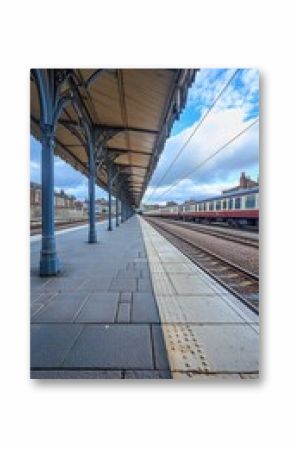 Empty train platform with a train waiting on a cloudy day