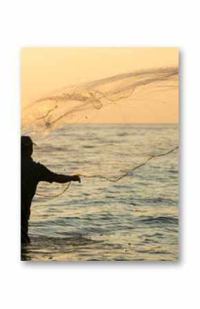 Silhouette of the unidentified Indian fisherman throwing net in sea on sunset in Fort Kochi, India.