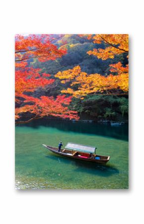 Boatman punting the boat for tourists to enjoy the autumn view along the bank of Hozu river in Arashiyama Kyoto, Japan.