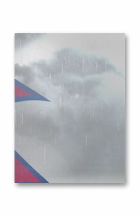 fluttering Nepal flag showing sun and moon symbols under gray sky, with falling rain, copy space