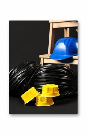 Stepladder with hardhat, rolled wires, extension cable reels and electrical junction boxes on black background