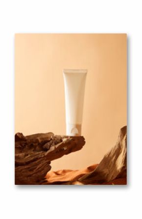 Unlabeled white tube of cream stand at the tip of a rough rock outcrop. The burnt orange sand has an uneven surface, forming undulating sand dunes. A undulating log with regular grain patterns