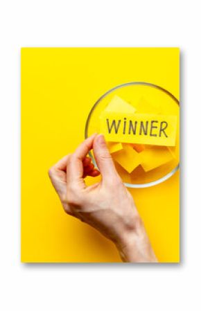 Hand is holding raffle ticket winner near glass jar, top view. Luck and lottery concept