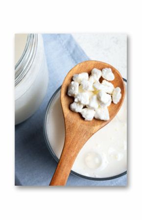 Milk kefir grains on wooden spoon and jar of kefir