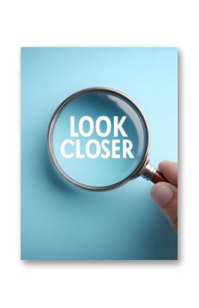 Hand holding magnifying glass showing look closer text on blue background