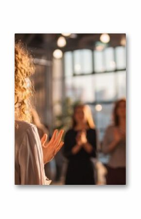 The woman presenting to an applauding audience in an inspiring workshop setting.