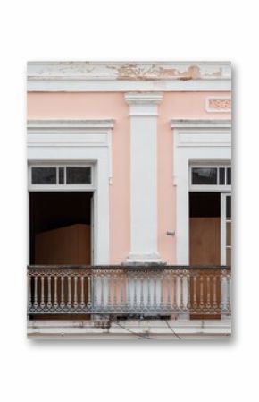 Historic facade of a pink building with white columns and a balcony, dated 1868