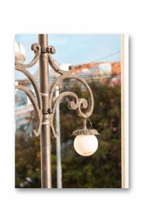 Close-up of street lamps on a sunny day with blurred trees and buildings in the background