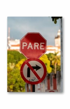 Close-up of a stop sign and no right turn sign with a blurred city background