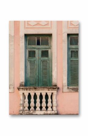 Vintage architecture with green shutters on a pink wall, featuring a classic balustrade