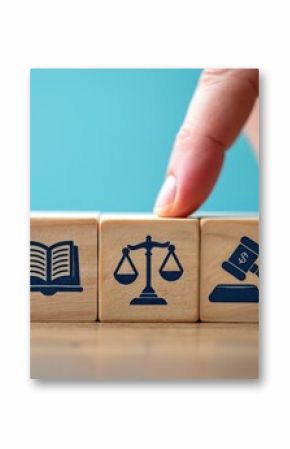 Wooden blocks showcase icons of law, justice, and finance. A finger selects a block, symbolizing choice in legal decisions and fairness. Represents legal system, court, and financial regulations.