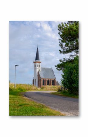 Typical landscape of Texel island with small village and picturesque church (Hervormde kerk) under blue sky and white clouds, A little town on the wadden islands, Den Hoorn, Noord Holland, Netherlands