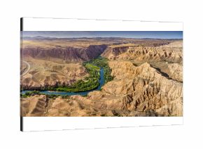Impressive panorama of Charyn Canyon in Kazakhstan, featuring a meandering river and unique rock formations under a clear blue sky