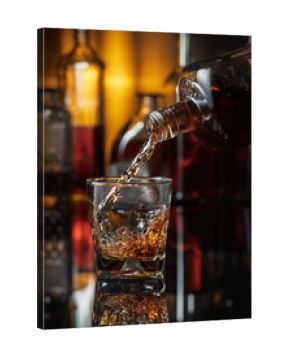 Pouring whiskey from a bottle into a glass.