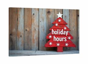 Red wooden Christmas tree decoration displays holiday hours text. Rustic sign with snowflakes on weathered planks. Seasonal retail shop information. Festive copy space.