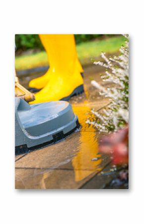 Pressure Washer Cleaning Patio Tiles With a Person in Yellow Boots on a Sunny Day