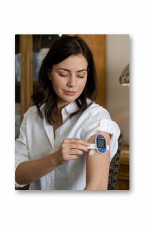 Woman using continuous glucose monitoring system at home