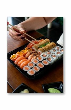 Chopsticks picking sushi from a platter