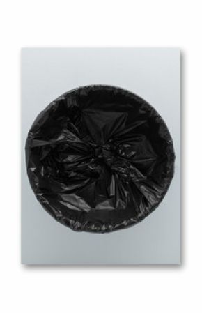 New empty dark black opened plastic garbage bag on light gray table background. Closeup. Top down view.