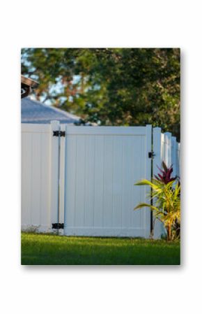 White vinyl picket fence on green lawn surrounding property grounds for backyard protection and privacy