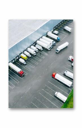 Aerial view of different logistic trucks at the loading docks of a large distribution warehouse. Drone photo.
