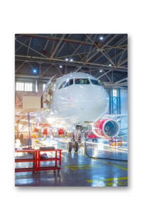 Passenger aircraft jet on maintenance of engine and fuselage repair in airport hangar red and blue backlight
