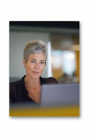 Focused mature business woman working at laptop in corporate office, showcasing professionalism and commitment to her work