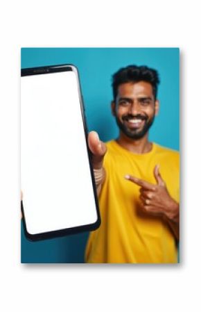 Happy indian man points finger at smartphone. Mobile app advertisement, modern tech. Smiling guy shows blank screen, copy space blue background. Presentation, digital marketing. Mobile phone display,