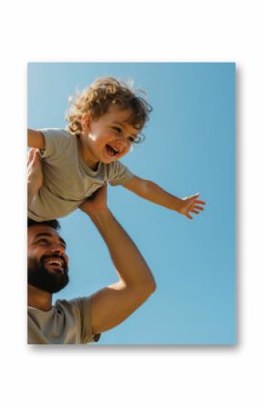 Happy bearded father lifting curly haired toddler son with arms spread against blue sky. Father's day celebration and family bonding activities