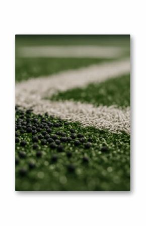 Black rubber granules scattered on artificial turf surface near white field marking on sports ground