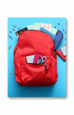 Red school backpack with different stationery supplies on blue background