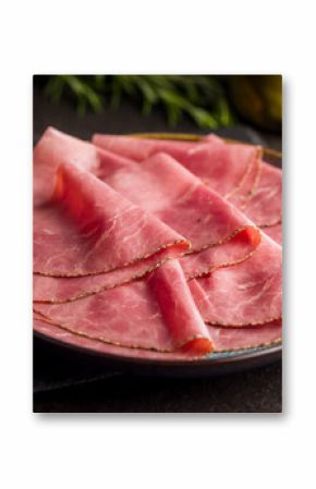 Sliced beef pastrami on plate on black table.