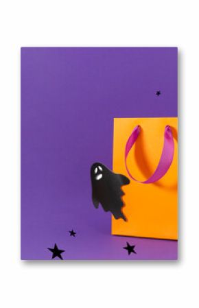 Gift orange bag with cute ghost and star decor on purple wall background. Halloween style shopping sale