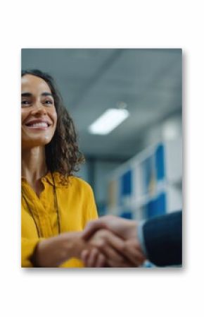 Medium shot capturing a studentathletes focused expression while shaking hands with a compliance officer after signing a NIL contract with office shelves softly blurred.